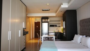 A modern hotel room with a large bed, a desk, and a kitchenette. - Island Letting-Crystal towers (Cape Town)