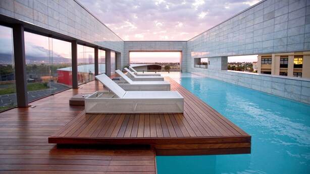 A rooftop infinity pool with lounge chairs and a wooden deck. - Island Letting-Crystal towers (Cape Town)