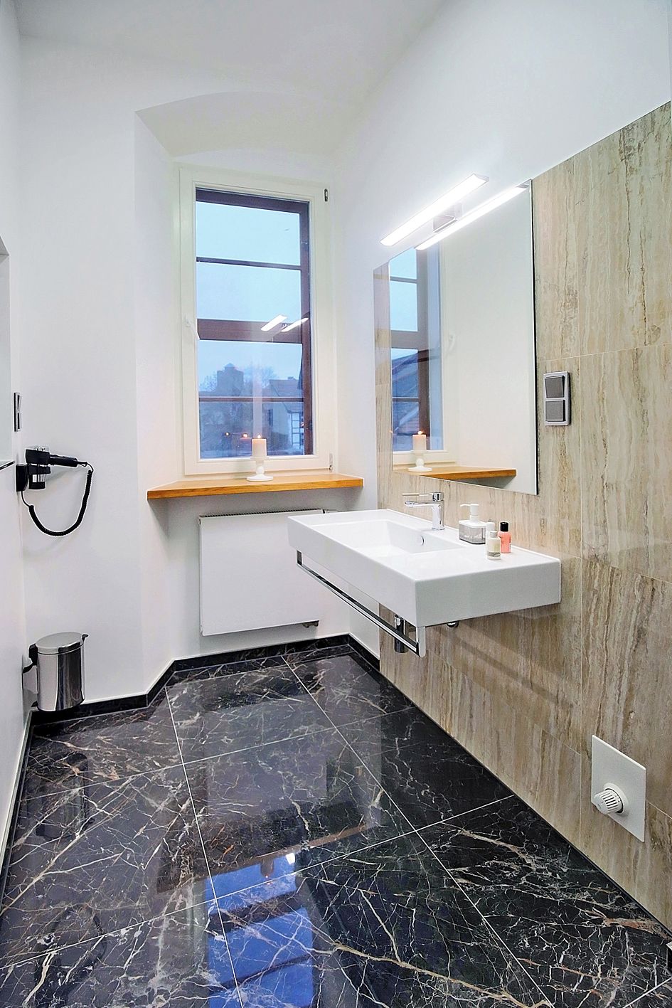 Un baño moderno con un lavabo blanco, un espejo y una ventana.