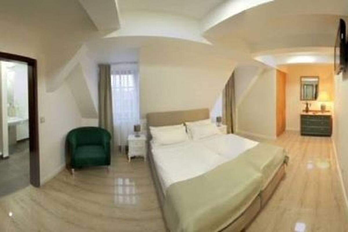 A hotel room with a bed, a chair, a dresser, and a mirror.
