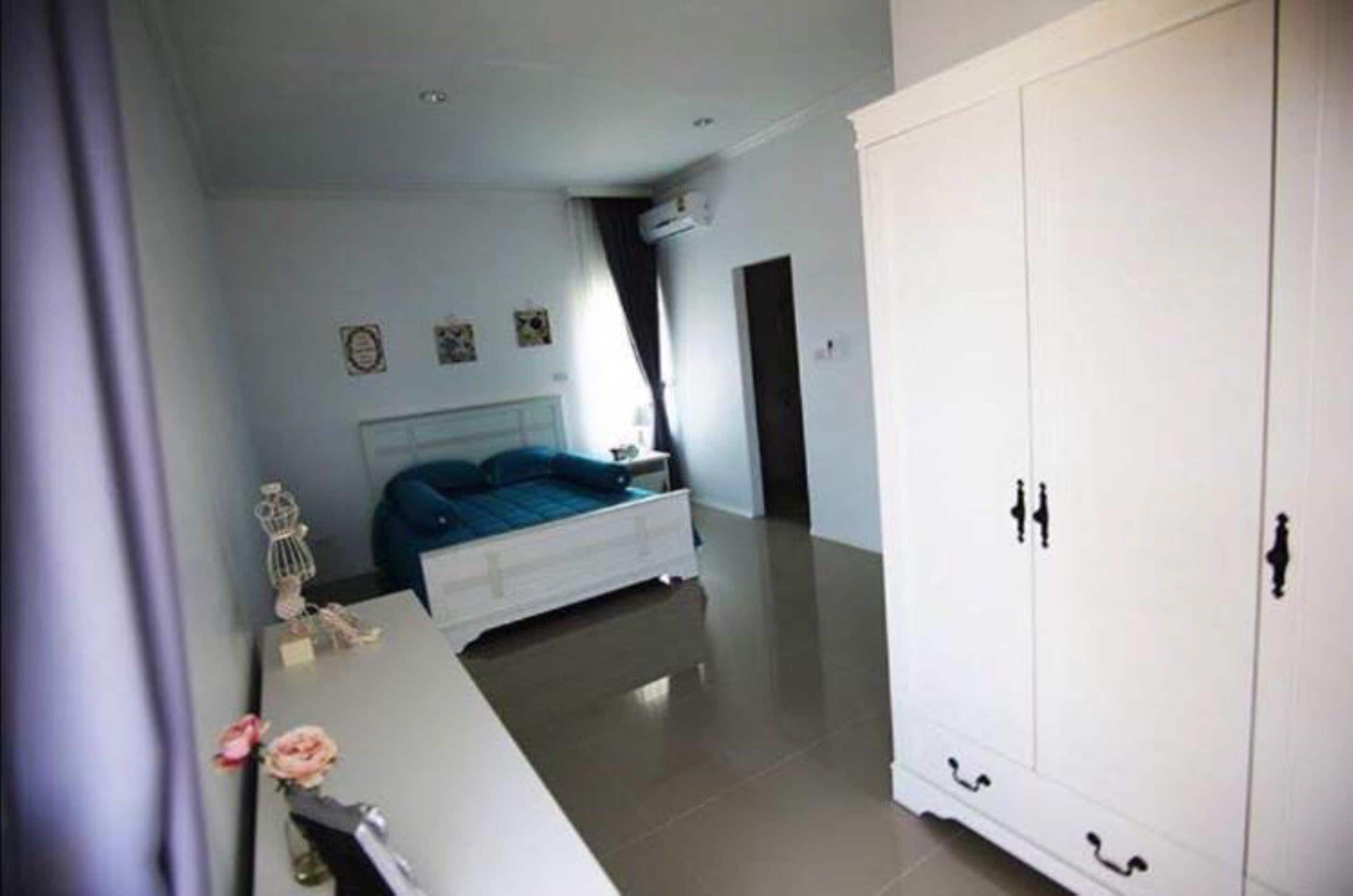 Una camera da letto con un letto, un armadio bianco e una scrivania con un vaso di fiori.