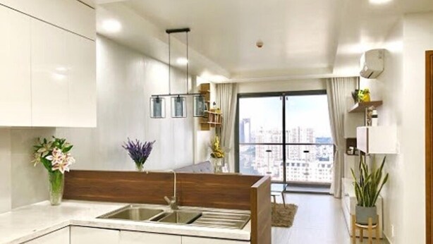 A modern kitchen with white cabinets, a wooden countertop, and a large window offering a city view. - The GoldView Luxury Apartment (Ho Chi Minh City)