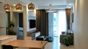 A modern living room with a sofa, TV, and a dining area with a table and chairs. - The GoldView Luxury Apartment (Ho Chi Minh City)