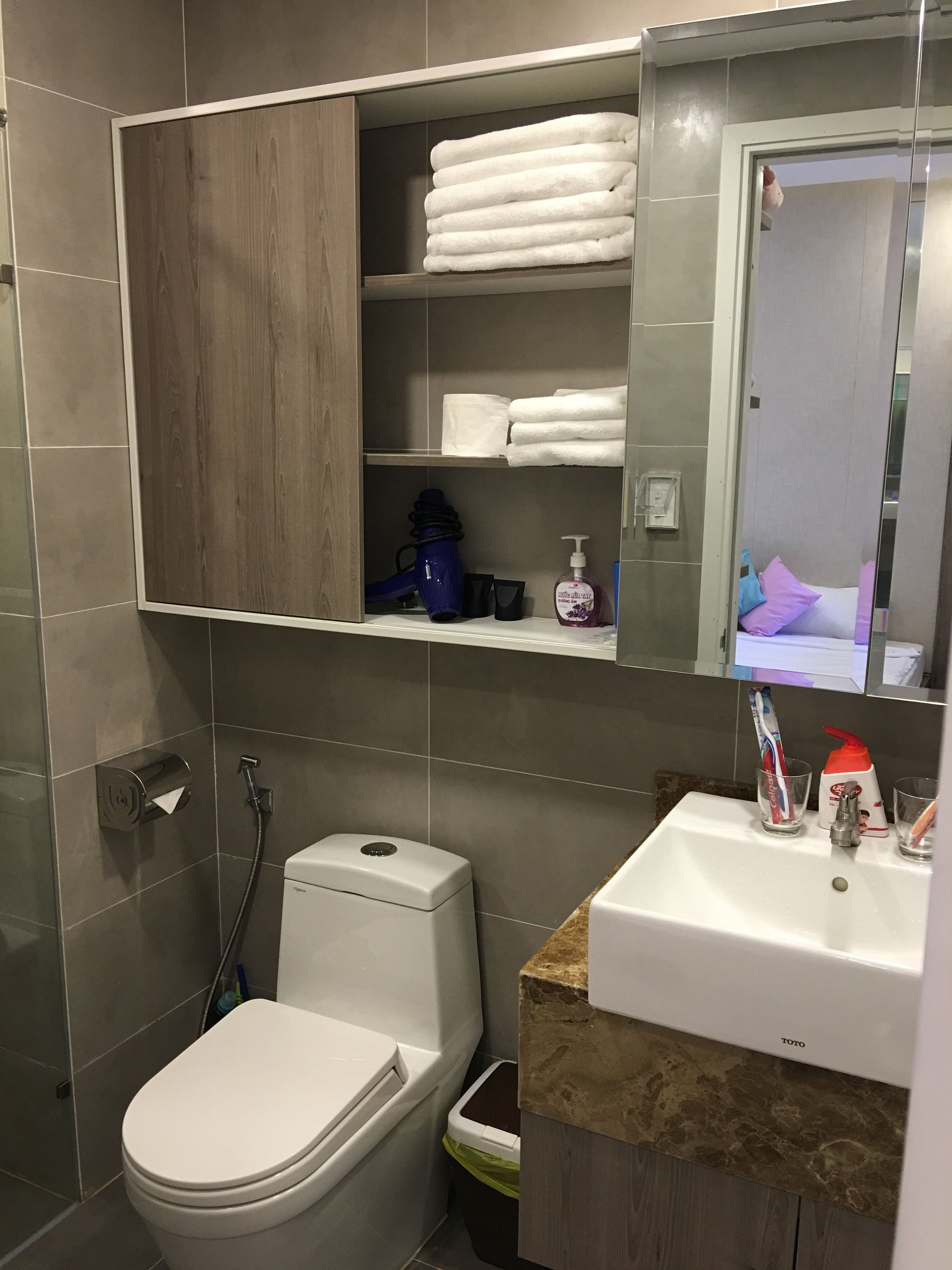 A modern bathroom with a toilet, sink, and a cabinet with towels.