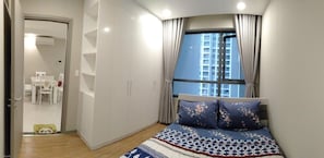 A bedroom with a bed, a window, and a door leading to a dining area.