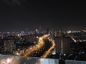 A nighttime cityscape with illuminated buildings and a busy road.