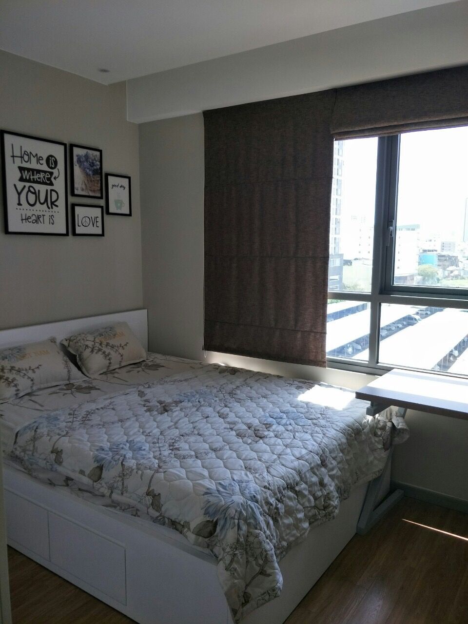 A bedroom with a large bed, a window with curtains, and motivational wall art.