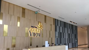 A reception desk with a sign reading "TNR The Gold View" in a modern lobby with a wooden panel wall and a tiled floor. - The GoldView Luxury Apartment (Ho Chi Minh City)