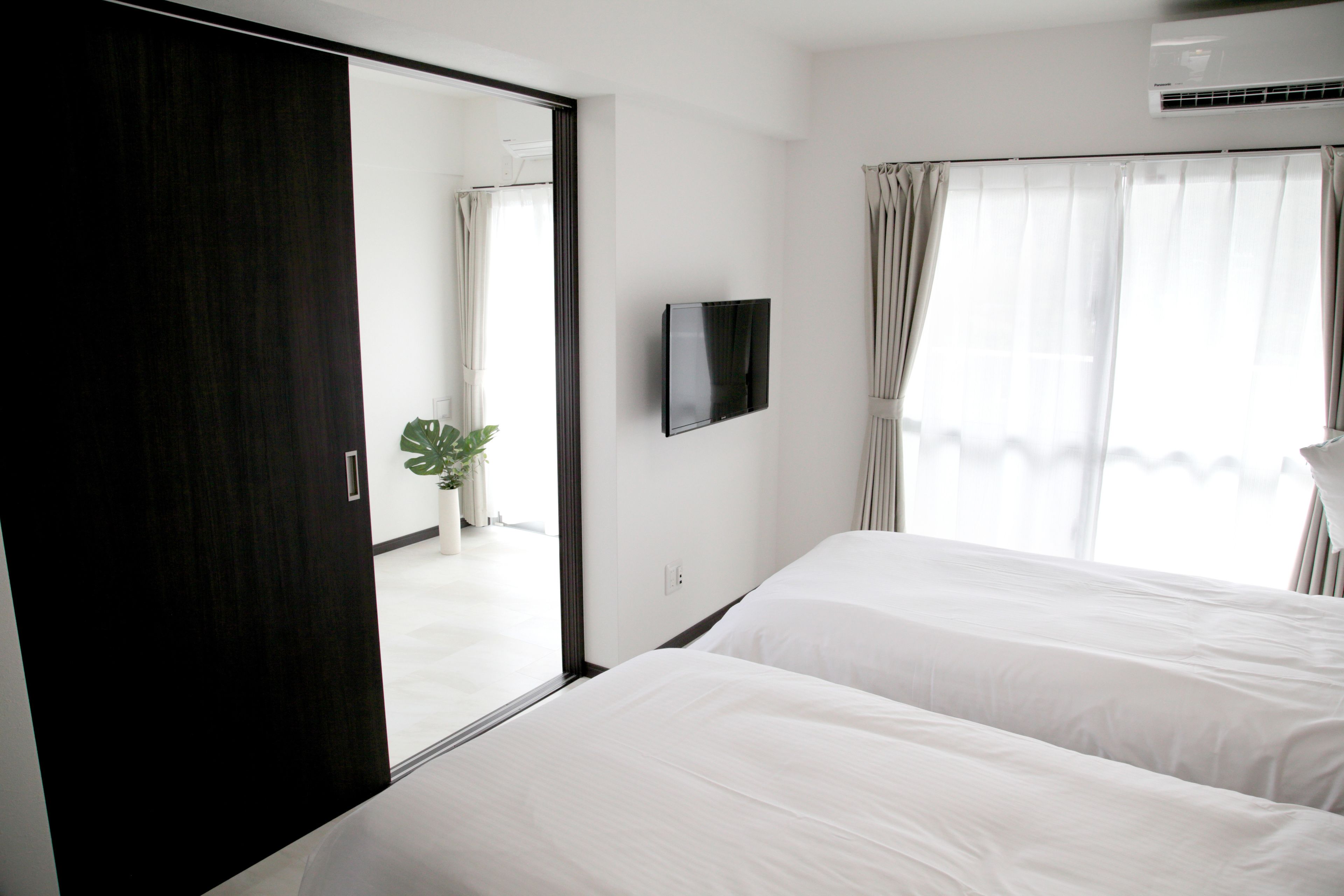 Habitación de hotel con un espejo grande, un televisor de pantalla plana y una planta en maceta.