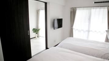 Habitación de hotel con un espejo grande, un televisor de pantalla plana y una planta en maceta.