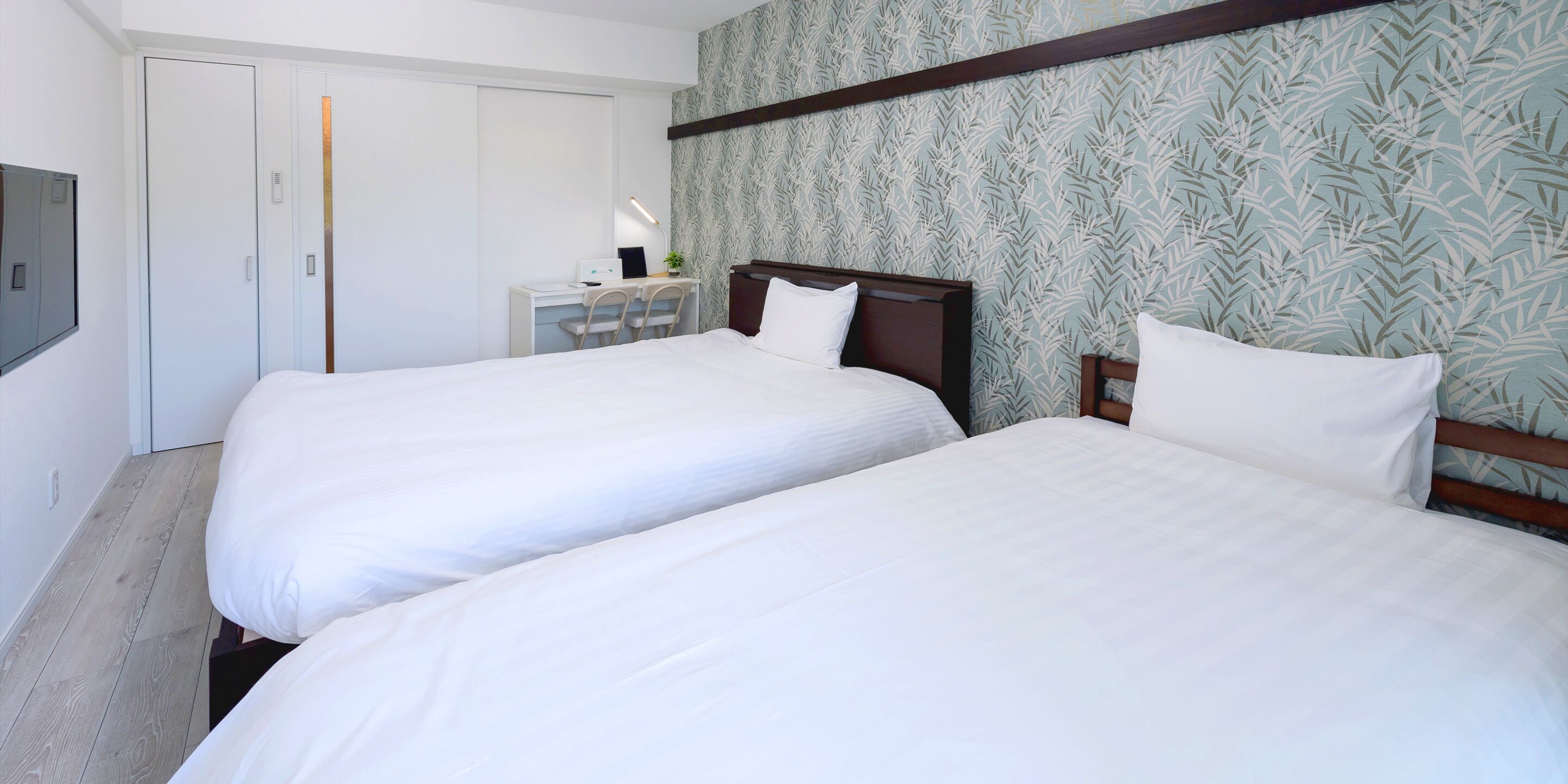 Une chambre d’hôtel avec deux lits, un bureau et une armoire.