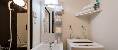 A bathroom with a white sink, mirror, and towel rack. There is a hairdryer and a bottle of hand soap on the counter.