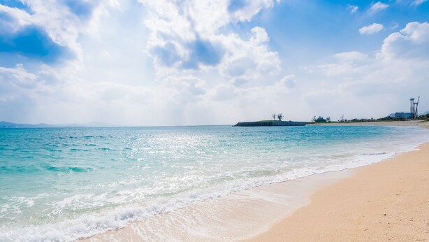 A beach with clear turquoise water, a sandy shore, and distant landforms. - Hotel Tomas Nago (Nago)