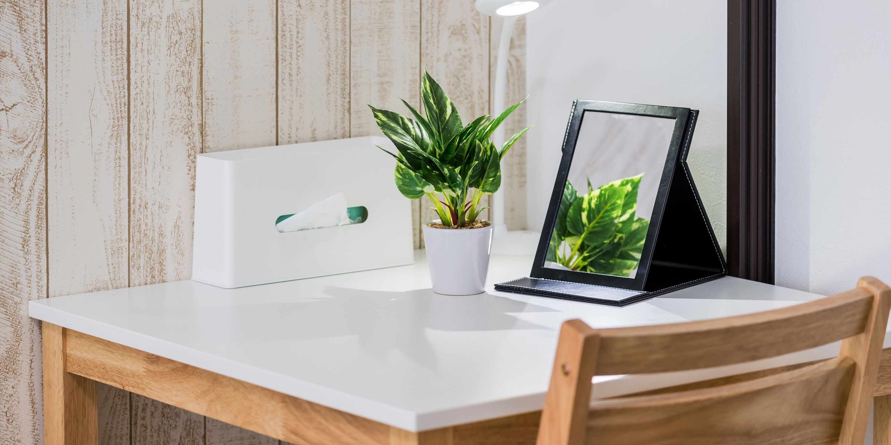 Una mesa blanca con una planta en maceta y un cuadro enmarcado.