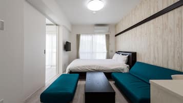 A modern hotel room with a bed, teal sofa, bench, and a wooden accent wall.