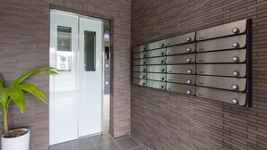 A hotel entrance with a modern elevator, a potted plant, and a wall with numbered room signs. - Hotel Tomas Nago (Nago)