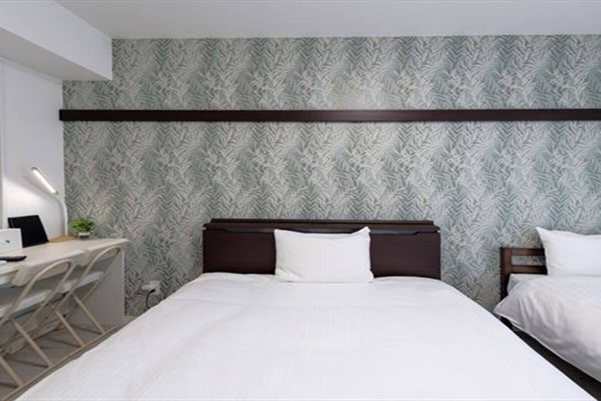 A hotel room with two beds, a desk, and a chair.