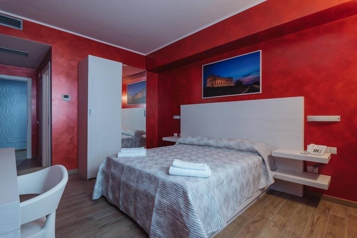 A modern hotel room with a large bed, a desk, and a chair.