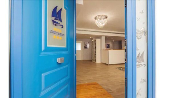 A hotel lobby with a blue door, a reception desk, and a chandelier. - Le Vele di Balestrate (Balestrate)