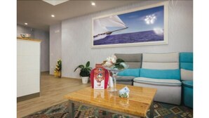 A modern living room with a sofa, a coffee table, and a painting of a sailboat on the wall. - Le Vele di Balestrate (Balestrate)