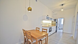 Cozinha moderna com armários brancos, uma mesa de jantar de madeira e um lustre.