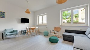 Uma sala de estar moderna com sofá, cadeiras, televisão e janelas amplas.