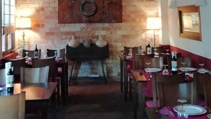 A dining area with brick walls, a fireplace, and tables set for dining. - Casa Antiquary (Benitachell)