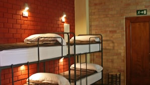 A room with three bunk beds against a brick wall, a wooden door, and a patterned rug. - Casa Antiquary (Benitachell)