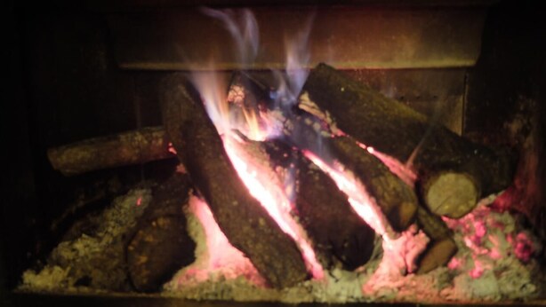 A fireplace with burning logs and smoke. - Hostal Rural La Casa del Peregrino (Molinaseca)