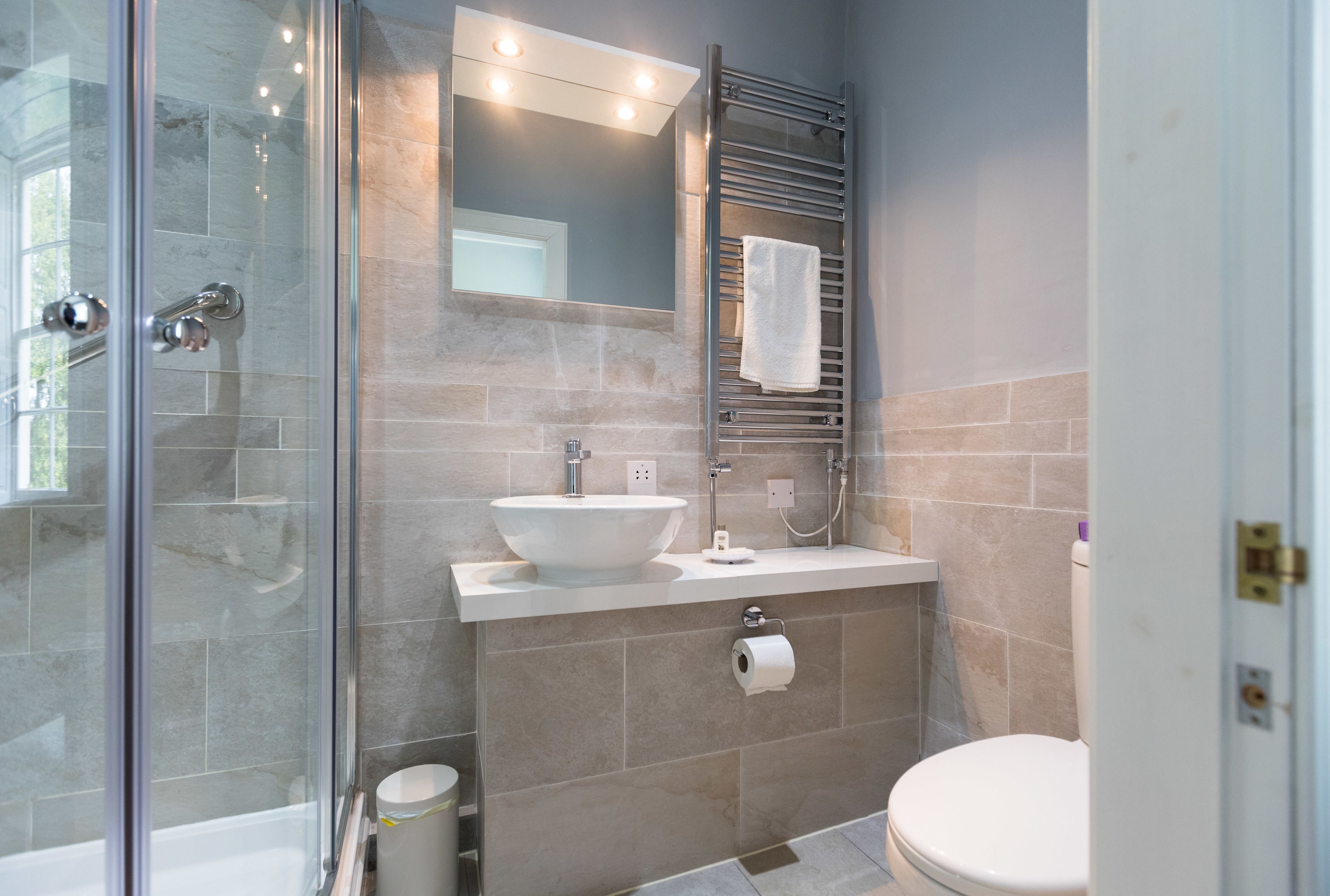 A modern bathroom with a glass shower enclosure, a white sink, and a toilet.
