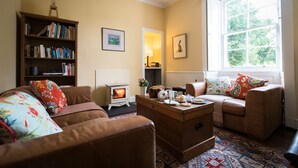 Uma sala de estar aconchegante com lareira, sofás, uma mesa de centro e uma estante de livros.