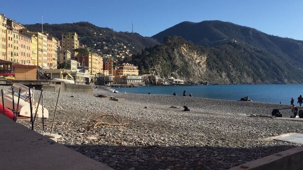 A pebble beach with buildings and mountains in the background. - House Camogli (Camogli)