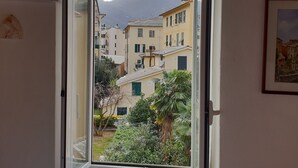 A room with a window opening to a view of buildings and a mountain. - House Camogli (Camogli)