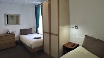 A hotel room with a bed, a dresser, a nightstand, a mirror, and a window with curtains.