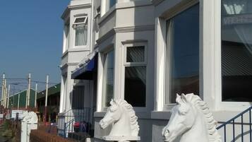 A row of white houses with a brick wall and a metal fence.