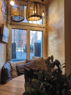 Una habitación con cama, ventana con vista a un edificio y una lámpara colgante.