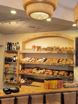 Mostrador de panadería con diversos productos horneados y una variedad de bebidas embotelladas.
