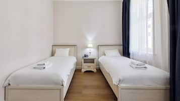 A twin room with two beds, a nightstand with a lamp, and a window with curtains.