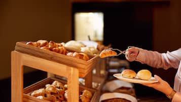 Buffet servindo diversos produtos de panificação, incluindo croissants e pães.