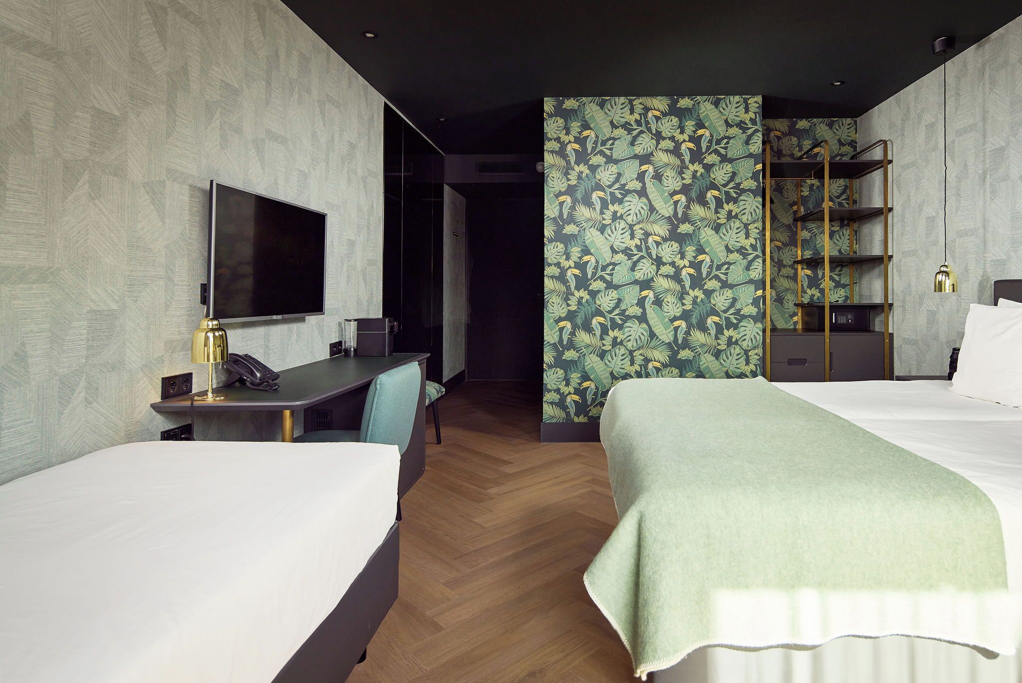 A hotel room with two beds, a desk with a chair, a TV, and a bookshelf.