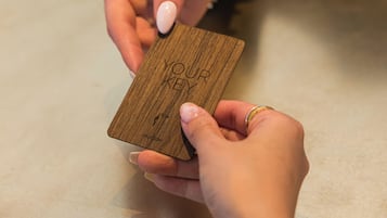 A person holding a wooden card with the text "YOU ARE KEY" and "WELCOME".