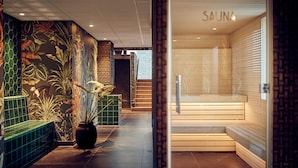 Kylpyläalue, jossa on sauna, mosaiikkiseinä ja oleskelualue.