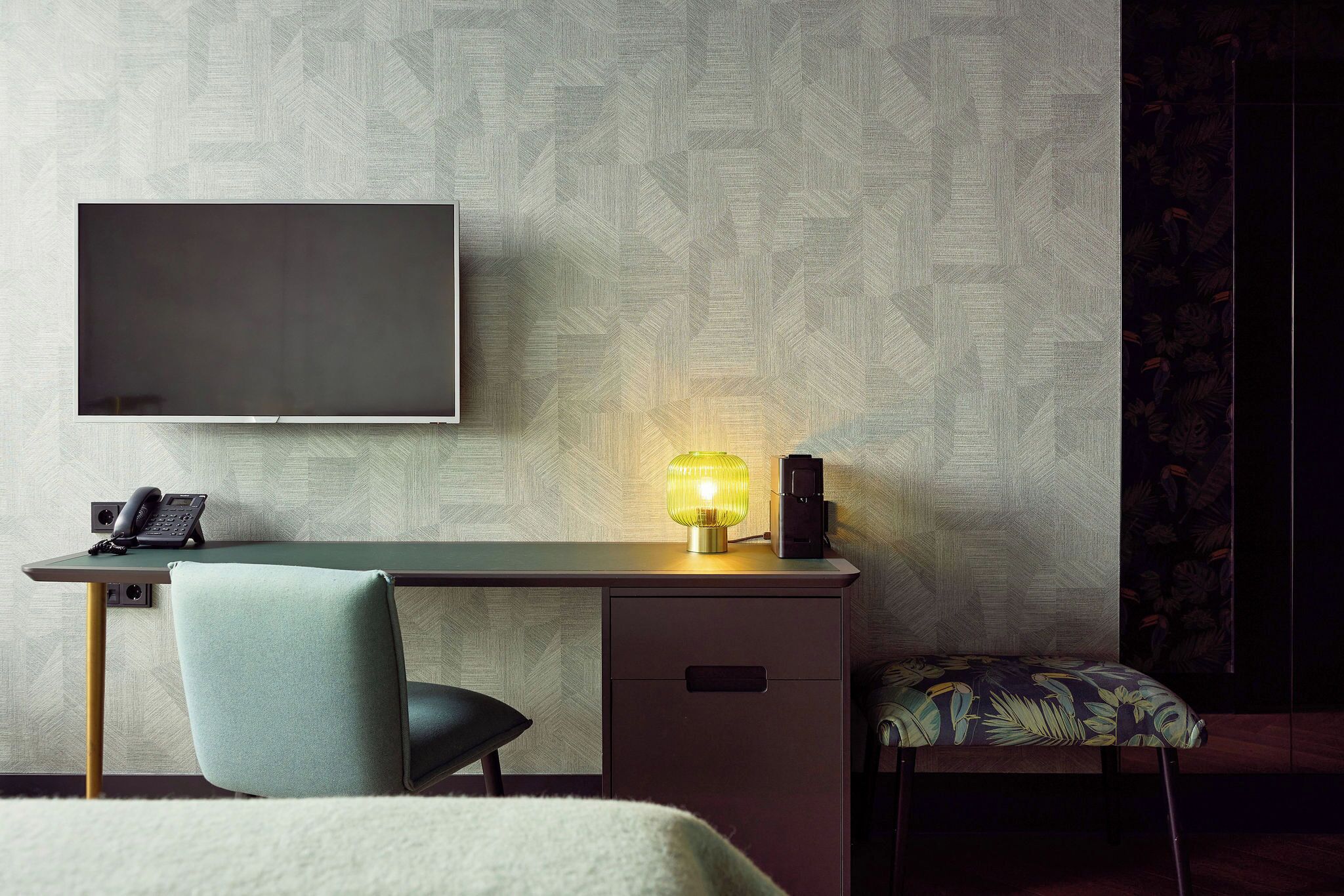 Una habitación de hotel moderna con televisión de pantalla plana, un escritorio con lámpara, una silla y una cama.