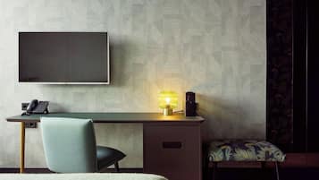 Una habitación de hotel moderna con televisión de pantalla plana, un escritorio con lámpara, una silla y una cama.