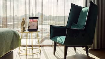 A room with a teal upholstered chair, a small round table with a gold base, and a framed sign on the table.