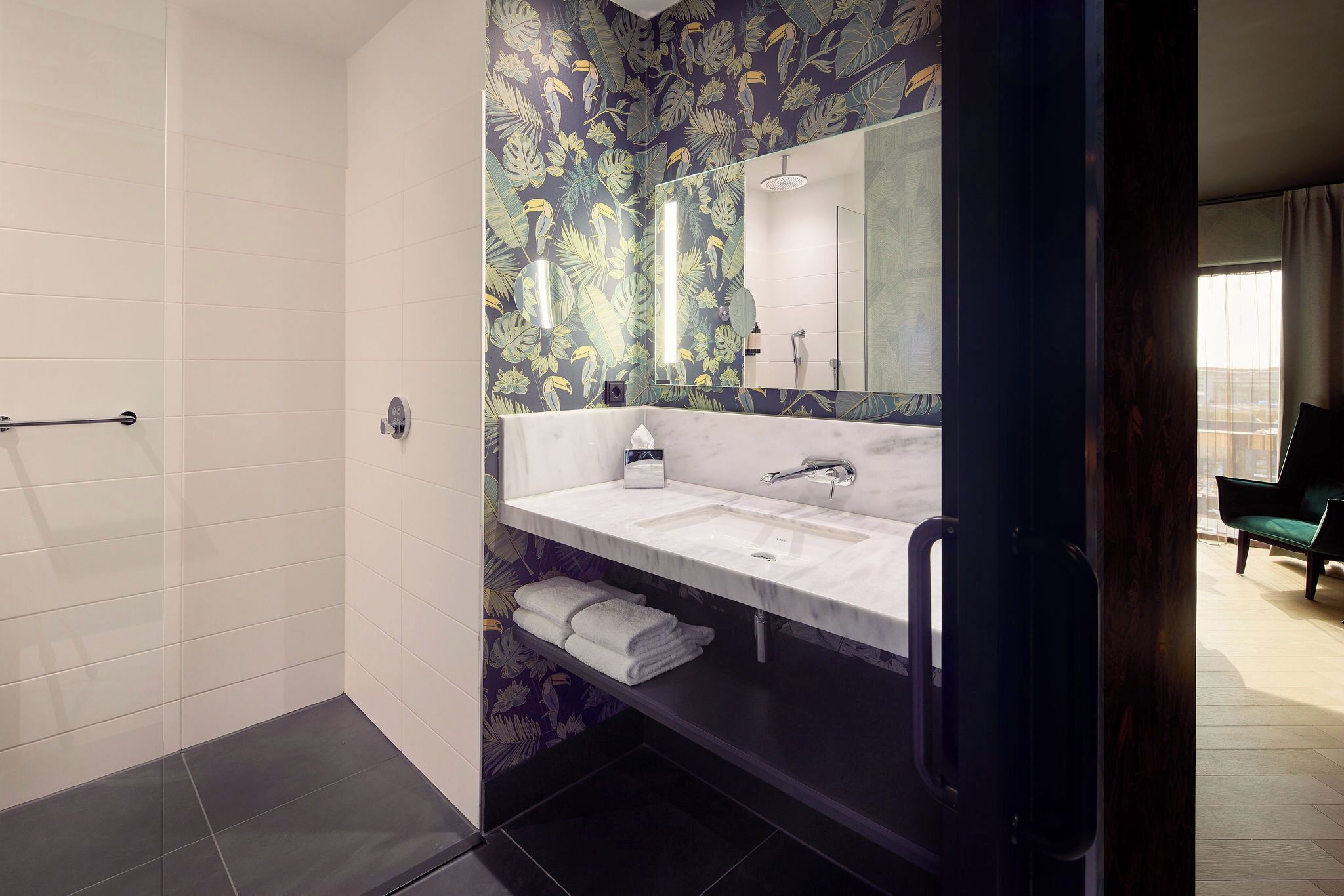 Un baño moderno con tocador blanco, un espejo grande y una zona de ducha.