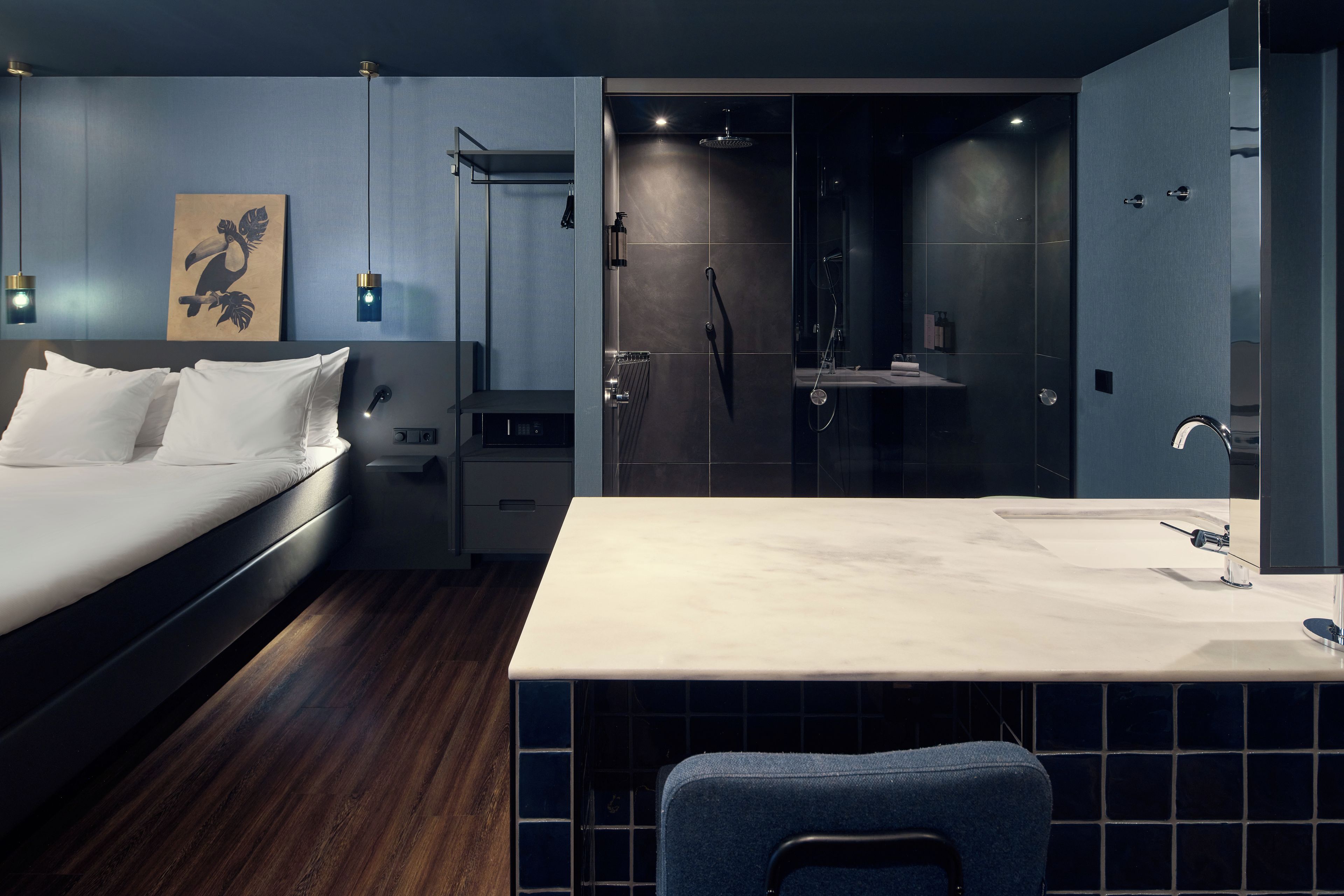 A modern hotel room with a bed, bedside table, and a bathroom with a shower and sink.