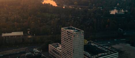 Un hotel moderno de gran altura con fachada de vidrio, rodeado por un paisaje urbano y un lago.
