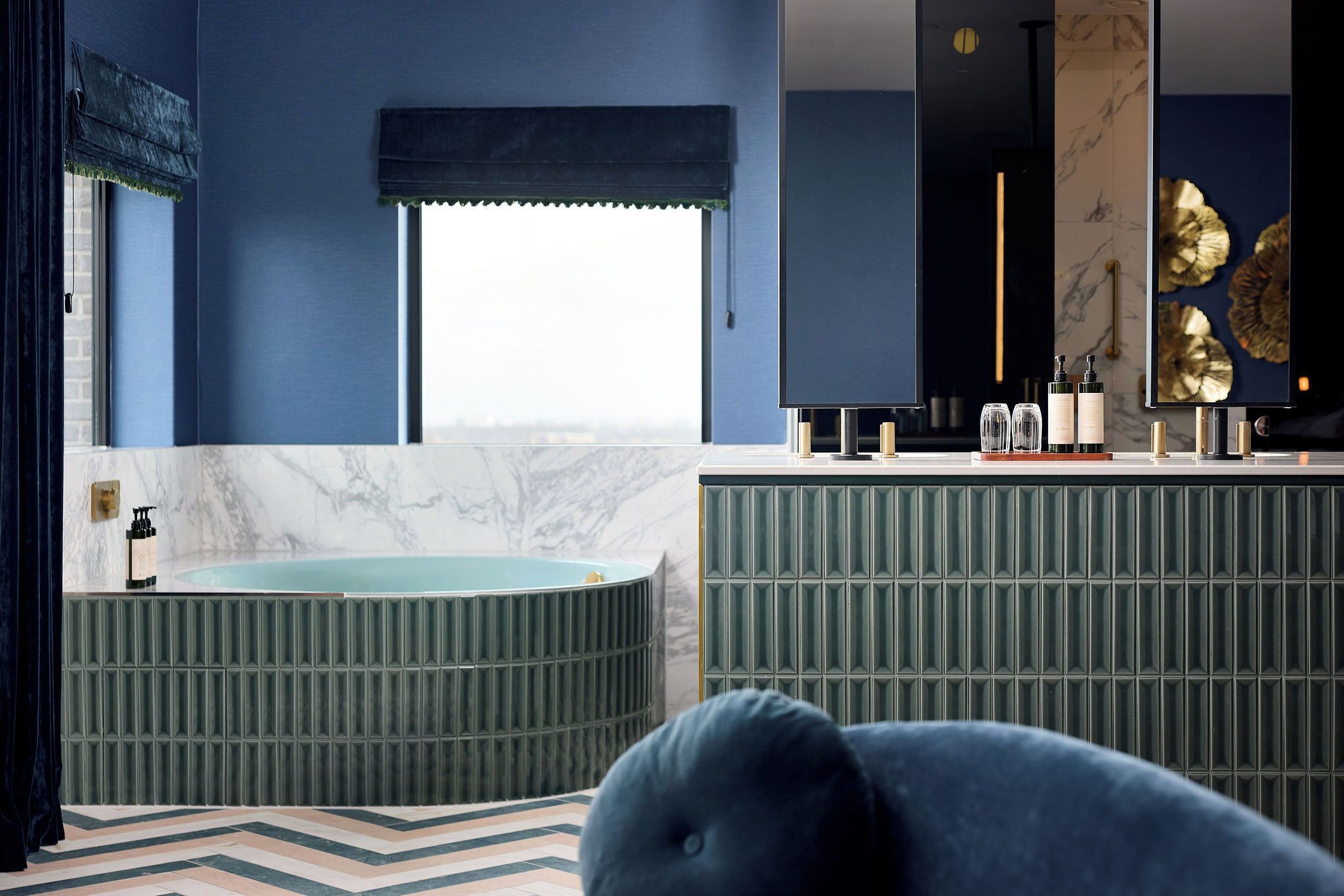 Un baño moderno con una bañera independiente, un tocador con espejo y un gran elemento decorativo en la pared.