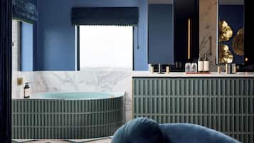 Un baño moderno con una bañera independiente, un tocador con espejo y un gran elemento decorativo en la pared.